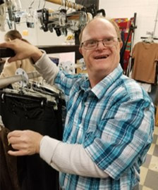 Donations Accepted link. Image of person served sorting donated clothing at resale store.