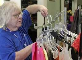 Photo of person receiving services hanging clothing at Freedom Treasures resale store.